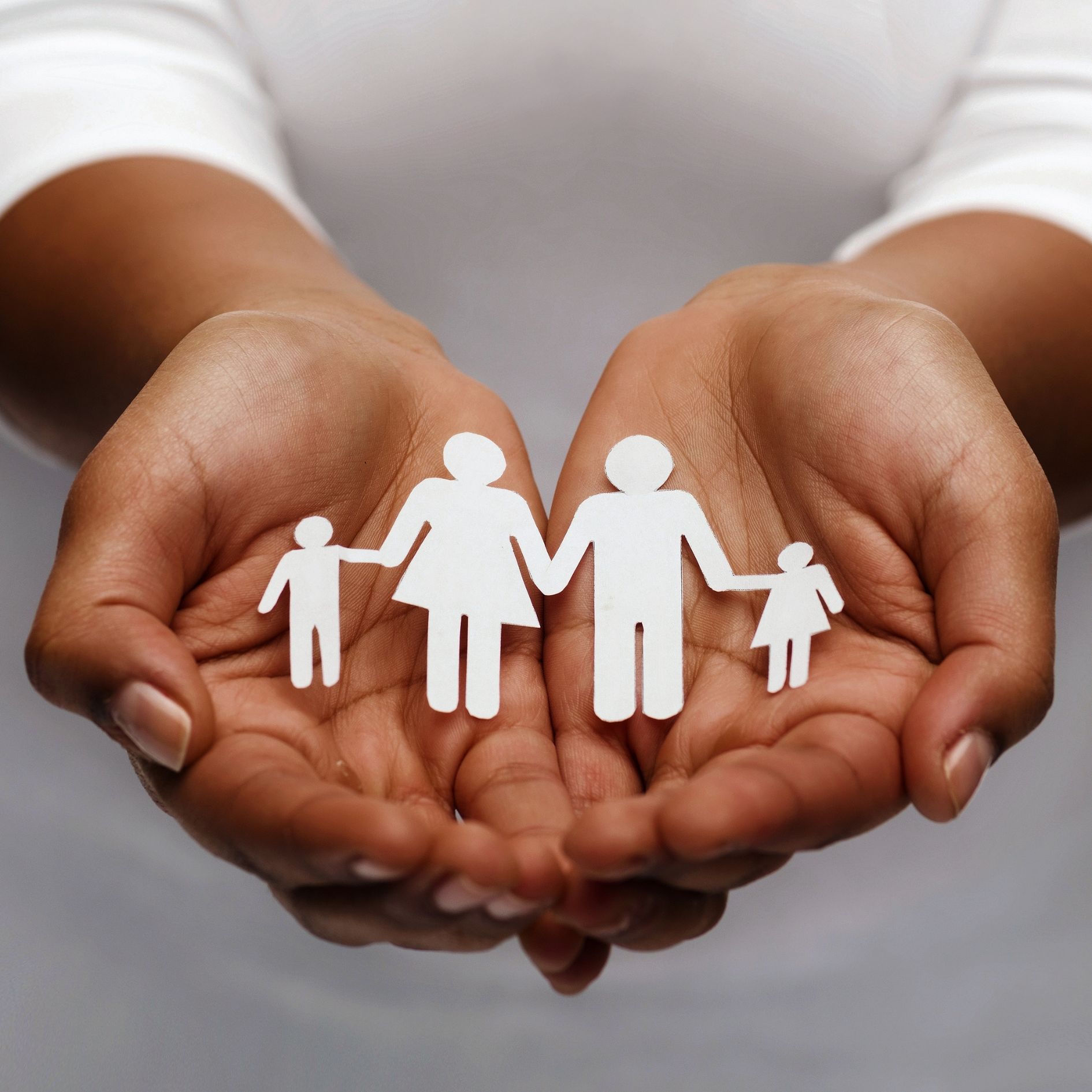 Hands holding paper cut out family