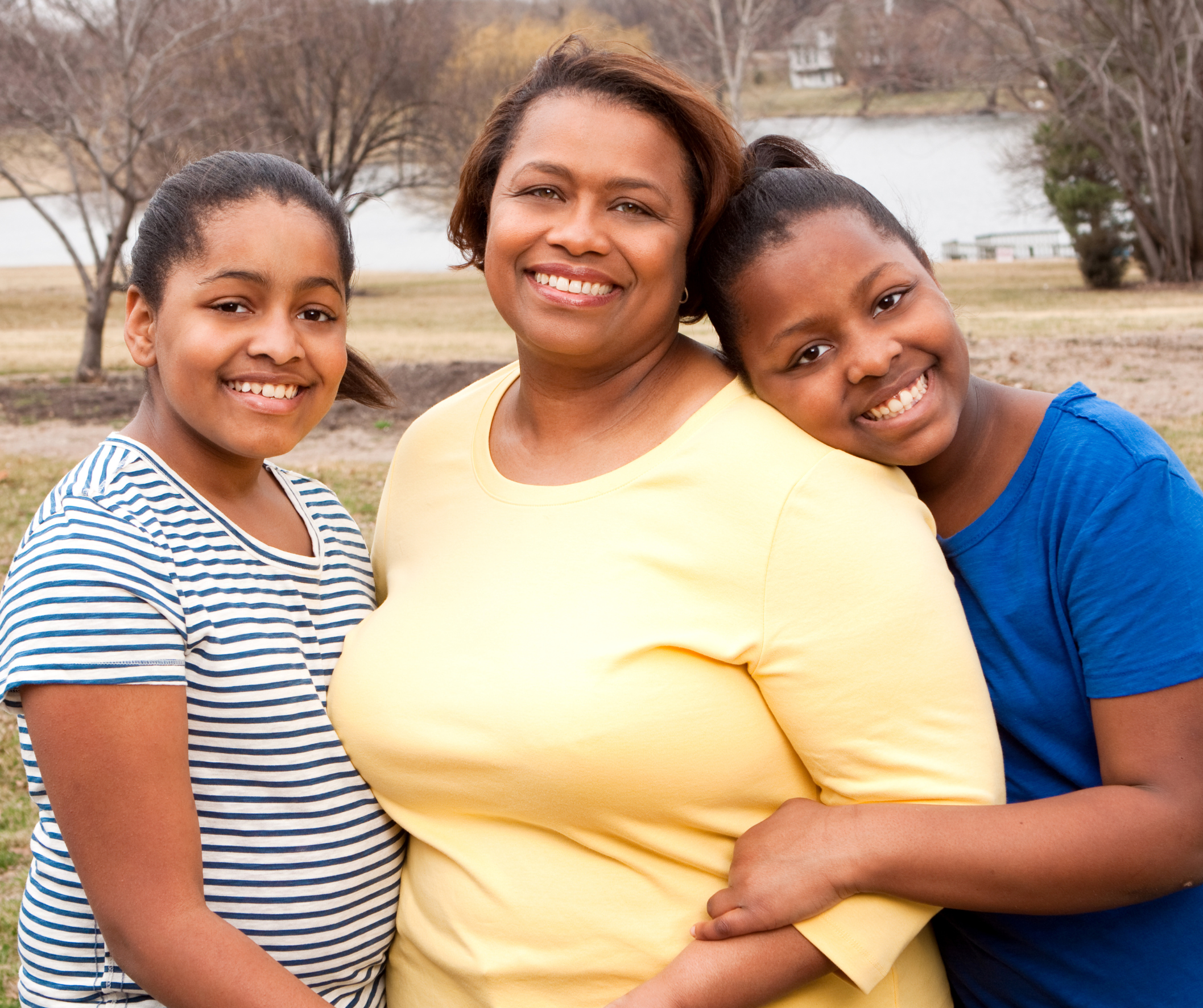 Mother with hewr two teenage daughters in a park by a lake