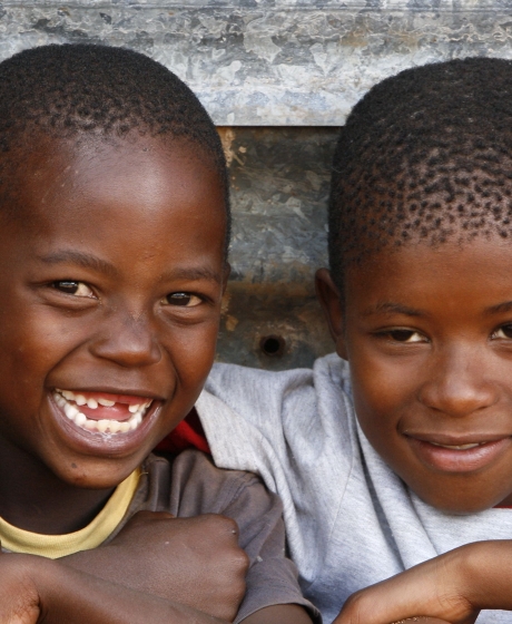 Two kids laughing and arms around their shoulders