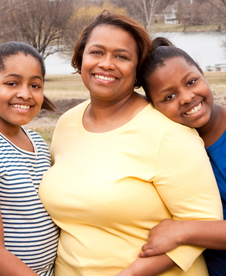 Mother with hewr two teenage daughters in a park by a lake