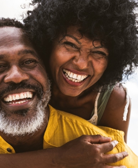African couple smiling with wife on husband's shoulders